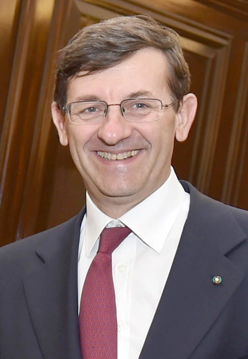 Portrait photo of Vittorio Colao in a suit and tie, smiling indoors