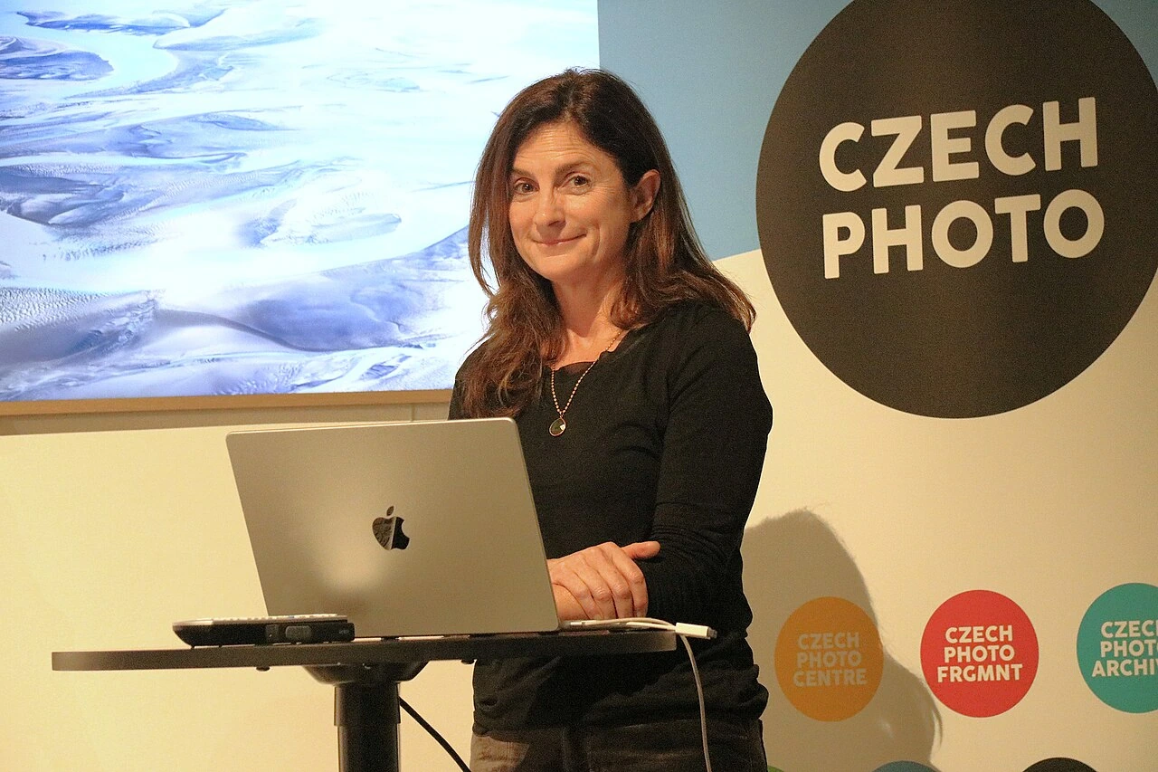 Ami Vitale speaking at an event in front of a laptop and a Czech Photo sign