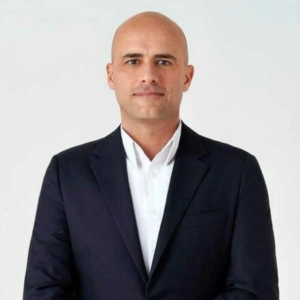 Portrait photo of Massimo Vian in a dark suit against a light background.