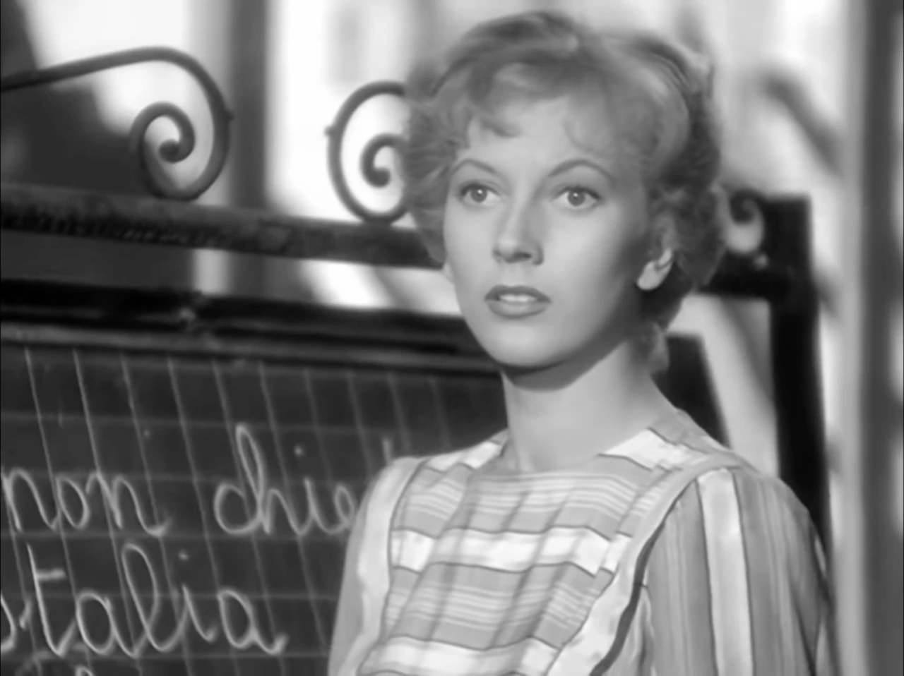 Valentina Cortese in a black-and-white film still, looking off-camera in a striped dress.