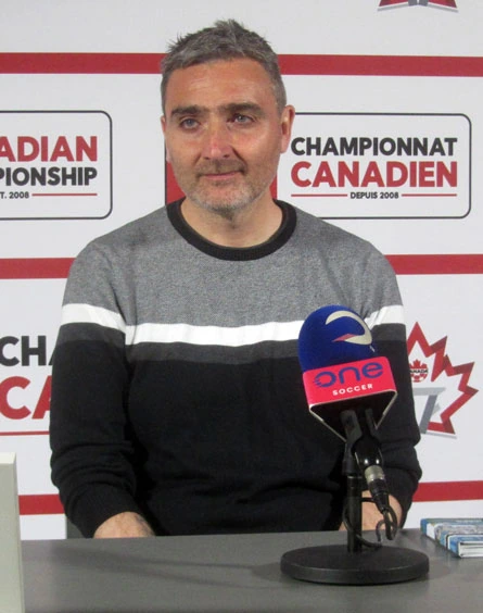 Vanni Sartini at a press conference, seated behind a microphone with a Canadian Championship backdrop