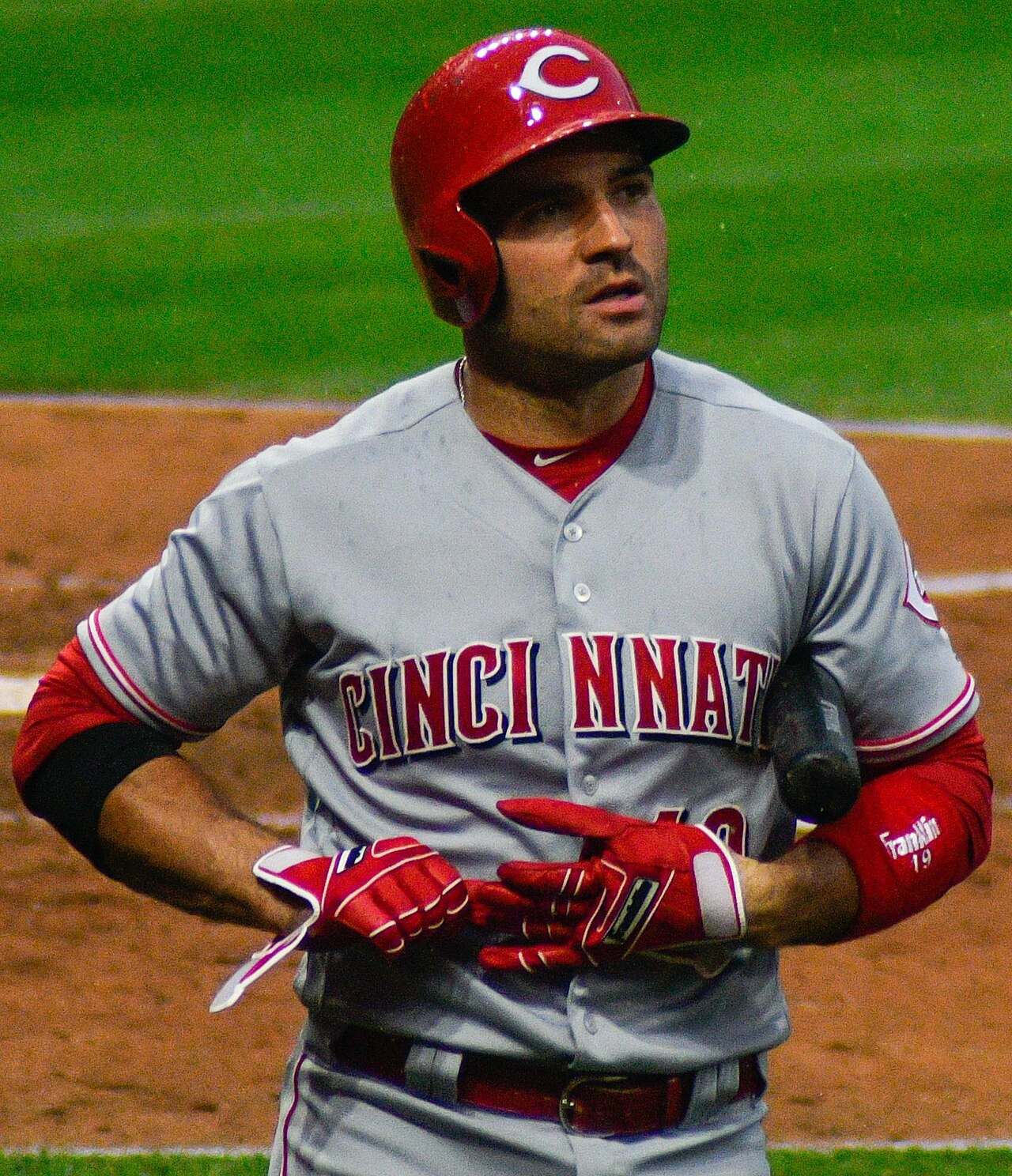 Joey Votto in a Cincinnati Reds uniform during a game, wearing a batting helmet and gloves.