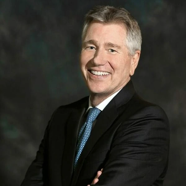 Portrait of a smiling man in a suit and tie against a dark studio background
