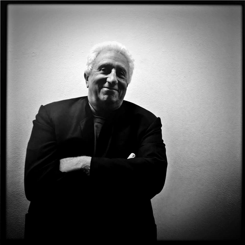 Black-and-white portrait of Massimo Vitali standing with arms crossed against a plain wall.